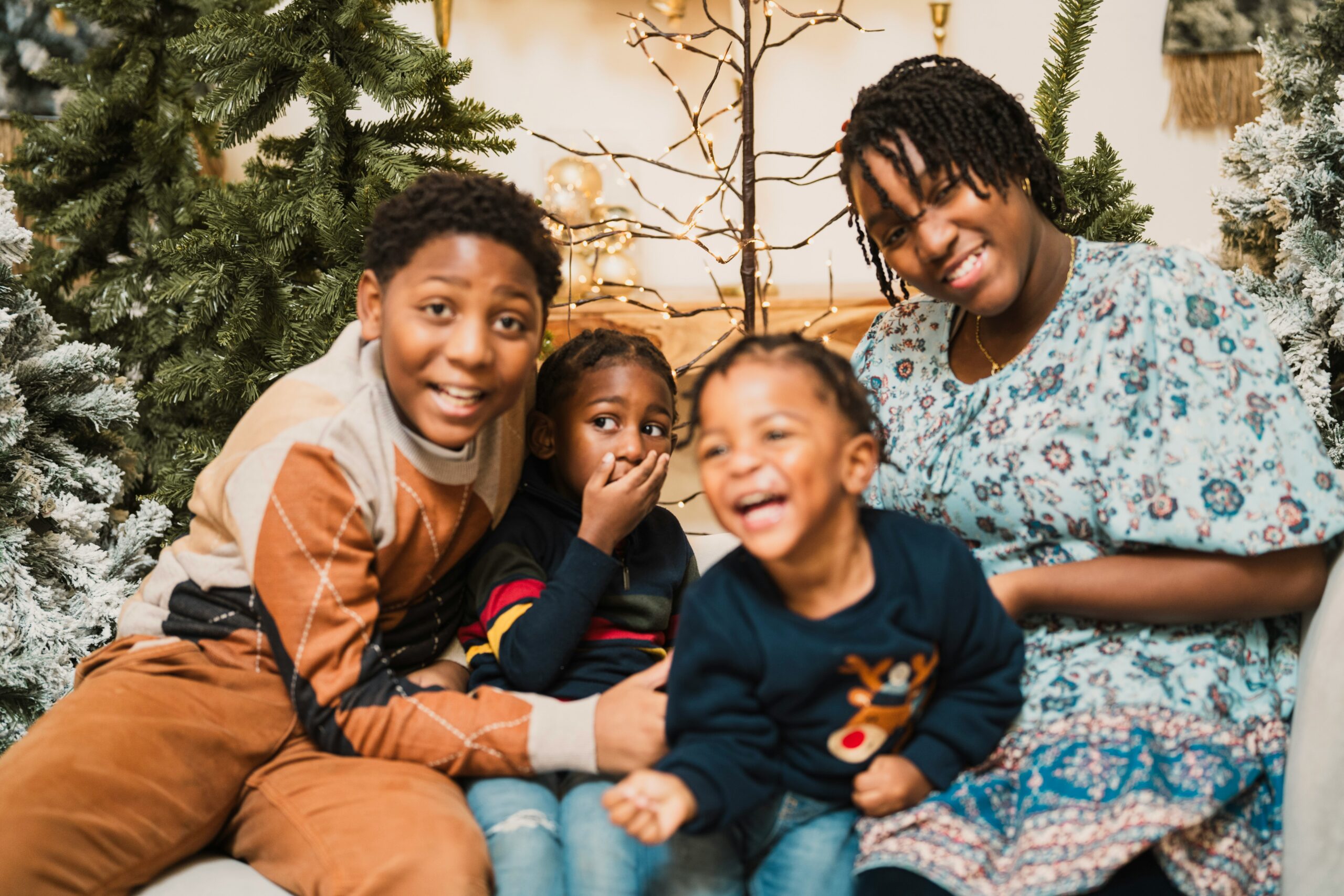 Wrapped in Hope at egm: a mother and her three children laughing together beside a Christmas tree